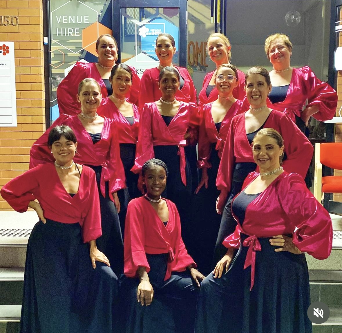 Dance group in pink satin tops posed outside venue
