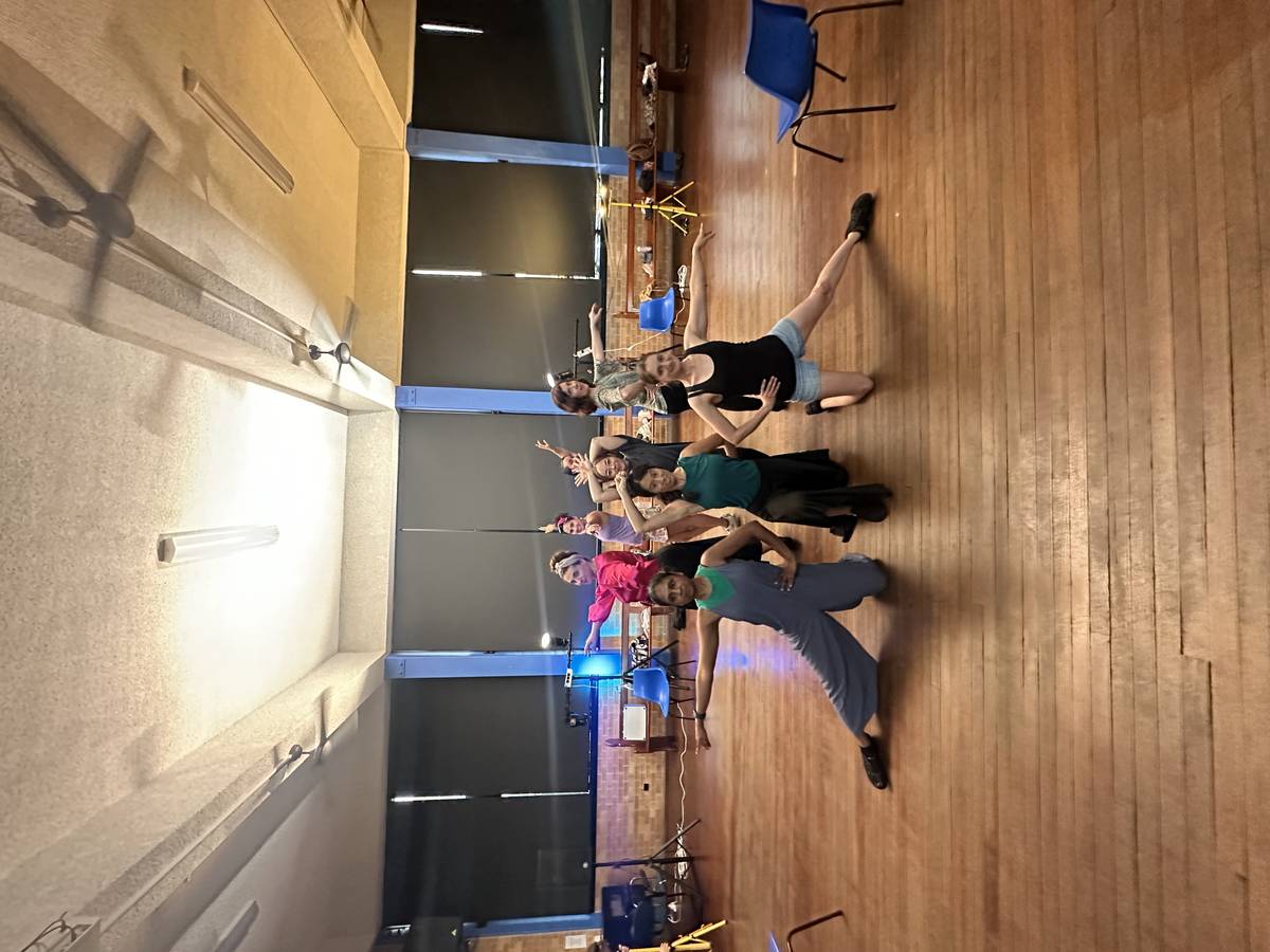 Dance workshop in community hall — arms raised, joyful movement